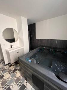 a bathroom with a large tub and a mirror at Coin de paradis avec spa illimité en plein centre Avranches in Avranches