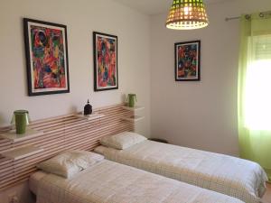 1 dormitorio con 2 camas y lámpara de araña en Maré Cheia, en Tavira