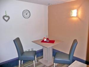 a table and chairs in a room with a clock on the wall at Ferienwohnung Jan in Prohn +6 photos