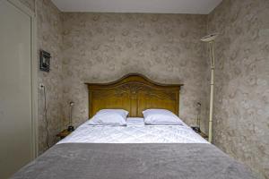 Schlafzimmer mit einem großen Bett mit einem Kopfteil aus Holz in der Unterkunft Les Goélands maison avec vue sur port et falaise in Fécamp