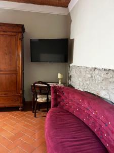 um quarto com uma cama roxa e uma televisão em A.G. Rooms in casa colonica em Vaiano