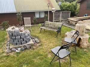 a yard with a bench and chairs in the grass at Dakune Chill - The Chalet in Ohakune