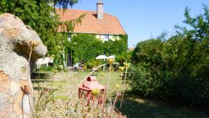 einen Hof mit einem Haus und einem roten Tisch mit einem Regenschirm in der Unterkunft Au Bonheur De Ce Monde in Boudreville