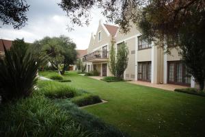 ein großes weißes Haus mit einem grünen Hof in der Unterkunft Southern Sun Bloemfontein in Bloemfontein