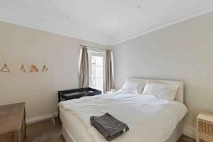 ein Schlafzimmer mit einem weißen Bett und einem Fenster in der Unterkunft Modern 3 Bed Apartment in Tottenham in London