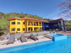 a yellow house with chairs and a swimming pool at Vista Mundo Centrar in San Ramón