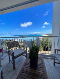 a balcony with a bench and a view of the ocean at Studio Epoustouflante Vue Mer St Martin in Saint Martin