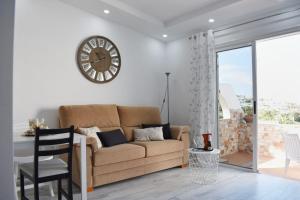 Ke Casetta Tenerife Anna Apartment في أديخي: غرفة معيشة مع أريكة وساعة على الحائط
