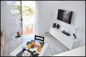 Ke Casetta Tenerife Anna Apartment في أديخي: غرفة معيشة بيضاء مع طاولة وتلفزيون