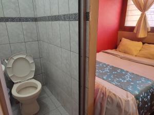 a small bathroom with a toilet and a bed at Casa de Sila in Cusco