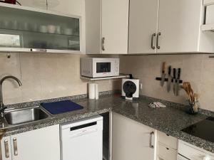a kitchen with white cabinets and a sink and a microwave at Apartamento casa típica canaria in Playa Honda