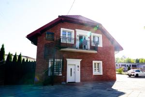 uma pequena casa de tijolos vermelhos com uma varanda em La Familia TYBURA em Uniejow