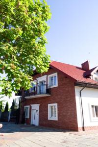 una casa de ladrillo con techo rojo en La Familia TYBURA en Uniejow