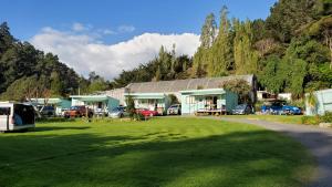 a house with cars parked in front of a grass field at Dickson Holiday Park in Thames