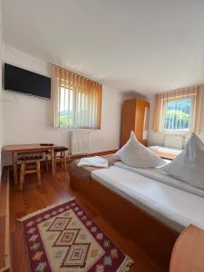Cette chambre d'hôtel comprend 2 lits, une table et des fenêtres. dans l'établissement Vila Cretu Bran, à Bran