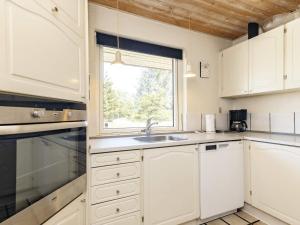 cocina con armarios blancos, fregadero y ventana en 10 person holiday home in Bl vand, en Ho