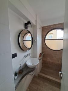 a bathroom with a sink and a round mirror at Departamento La Restinga - La Perla in Mar del Plata