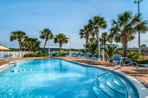 a swimming pool with blue chairs and palm trees at Pinnacle Port A-516 in Panama City Beach