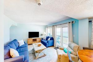 a living room with a blue couch and a tv at Pinnacle Port A-516 in Panama City Beach
