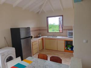 a kitchen with a refrigerator and a table and a sink at Maison zebre in Port-Louis