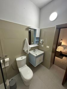 a bathroom with a toilet and a sink and a bed at Rus Villa in Berat