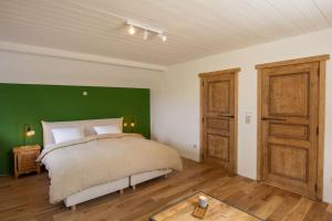 Au cœur des champs - Gîte في نيفيل: غرفة نوم بسرير مع جدار أخضر