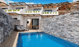 a villa with a swimming pool in front of a building at Aelia Suites in Agios Nikolaos