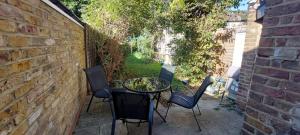 a patio with a table and chairs and a brick wall at Nice 3 Bedroom House Ealing in London
