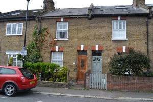 a red car parked in front of a brick house at Nice 3 Bedroom House Ealing in London