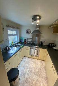 a kitchen with a stove and a sink at Nice 3 Bedroom House Ealing in London