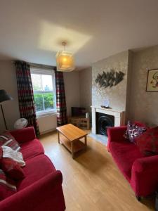 a living room with a red couch and a table at Nice 3 Bedroom House Ealing in London