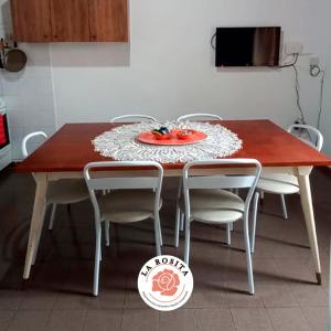 una mesa de madera con sillas y una placa roja. en La Rosita en Villa María