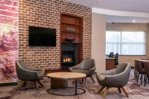 a lobby with a fireplace and chairs and a tv at Courtyard by Marriott Newark-University of Delaware in Newark