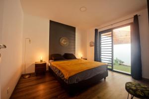 um quarto com uma cama e uma grande janela em Maison Moderne et Cosy proche de Papeete em Punaauia