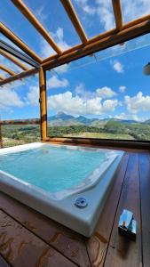 uma banheira de hidromassagem num deque com vista em Chalés Monte das Oliveiras em Domingos Martins