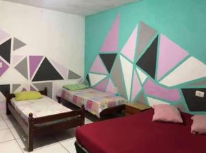 Pousada em Mongaguá Kali في مونغاغوا: غرفة بسريرين وجدار ملون