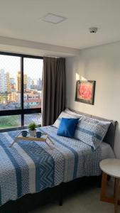 a bedroom with a bed with blue pillows and a window at Pérola do Bessa in João Pessoa