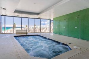 a large bathroom with a large swimming pool with green walls at Holiday Holiday Soul Apartments in Gold Coast +2 photos