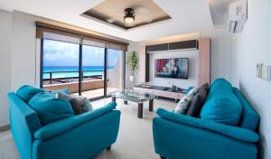 a living room with two blue chairs and a view of the ocean at Family Vacations apartment Ocean View in Cancún