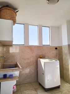 een keuken met een witte koelkast in een kamer met ramen bij Valentina House in Tacna