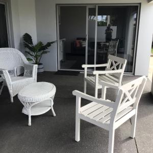 un grupo de sillas blancas y una mesa y una silla en Beachside studio, en New Plymouth