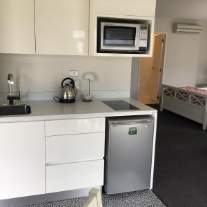 a kitchen with white cabinets and a microwave at Beachside studio in New Plymouth