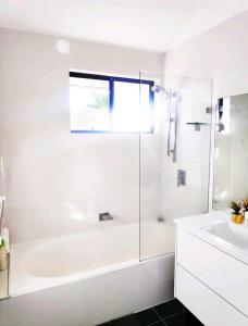 a white bathroom with a tub and a sink at ¶Pet Friendly Cosy Quite Room+TV+Sofa in Glenfield