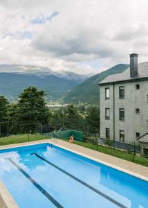 une piscine en face d'un bâtiment avec des montagnes en arrière-plan dans l'établissement Casa los Altos de Santiago, à Villanúa