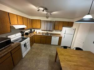 una cocina con armarios de madera y electrodomésticos blancos en Stay Anchorage! Furnished Two Bedroom Apartments With High Speed WiFi, en Anchorage
