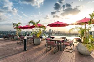 una terrazza con tavoli, sedie e ombrelloni rossi di Skynest - urban luxury apartments by El Mufasa a Nairobi