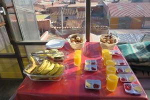 a red table with fruit and drinks on a table with a table at EUCALYPTUS POTOSI in Potosí