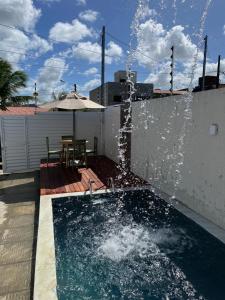 einen Pool mit einem Brunnen an der Seite eines Gebäudes in der Unterkunft Casa da Praia Carapibus in Conde