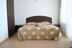 a bed with a brown and tan comforter in a bedroom at Apartments Helios in Pomorie +10 photos