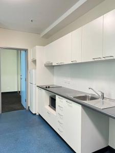 uma cozinha vazia com armários brancos e um lavatório em 2BR entire apt City central em Adelaide